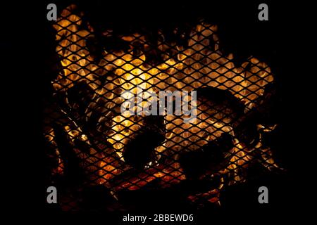 An outdoor fire in a heavy screen fireplace at night. Scene is dark except for the flames. Stock Photo