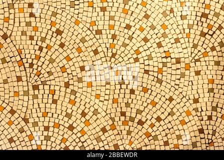 Looking straight down at a simple yellowish ceramic tile floor. It looks like the type of floor seen in a Roman or Greek villa. Tile exhibits a fan pa Stock Photo