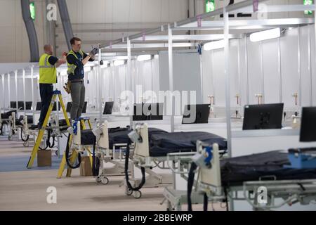 EMBARGOED TO 00.01 WEDNESDAY 01 APRIL Work continues at the ExCel centre in London which is being made into a temporary hospital - the NHS Nightingale hospital, comprising of two wards, each of 2,000 people, to help tackle coronavirus. PA Photo. Picture date: Tuesday March 31, 2020. A total of 1,408 patients have died after testing positive for coronavirus in the UK as of 5pm on Sunday. Photo credit should read: Stefan Rousseau/PA Wire Stock Photo