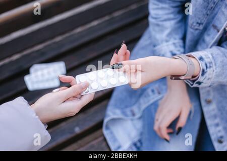 Women sharing pills in hands. Female give to woman tablets. Coronavirus theme Stock Photo