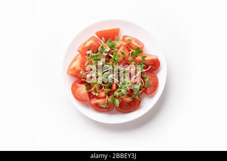 Fresh salad with tomato and microgreen radishes. Top view. Concept vegan and healthy eating. Isolated on white. Stock Photo