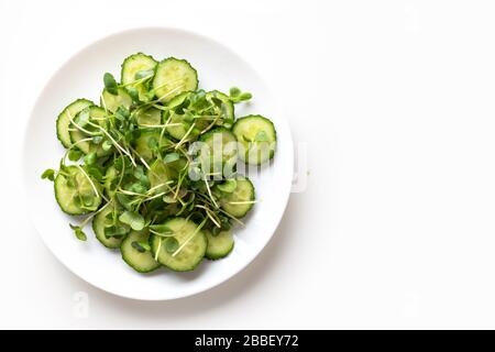 Fresh salad with cucumbers and microgreen radishes. Top view. Concept vegan and healthy eating. Isolated on white. Space for text. Stock Photo