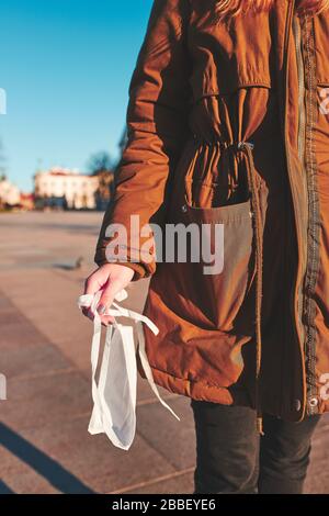 Girl holding the face mask. Ready to protect from virus infection and to prevent the spread of disease. Young woman walking in city centre. Virus infe Stock Photo