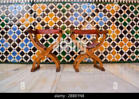 Granada, Spain: low angle view of marble floor and colorful wall tiles with chair with leather in front in the La Alhambra Stock Photo