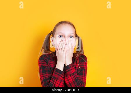 Photo of shocked little girl child over yellow background. Stock Photo