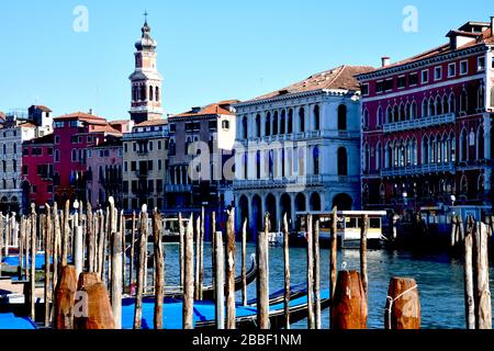 Venice, Italy-February 2020; View over Canal Grande in the direction of the Rialto bridge with in front the gondolas moored on the wooden poles- pali Stock Photo