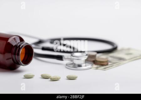 Health and medical expenses concepts: stethoscope and coins placed on banknotes as well as medicines. Stock Photo