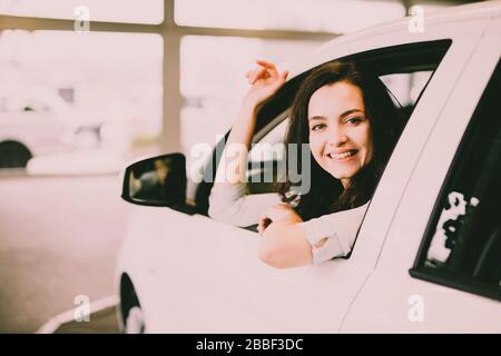 Cheerful laughing young woman sitting in a new car in a car dealership Stock Photo