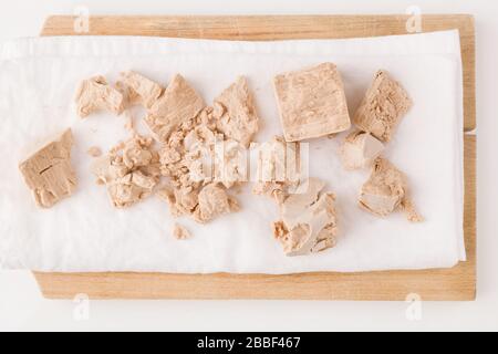 Fresh pressed yeast blocks on wooden board isolated on white background. Stock Photo