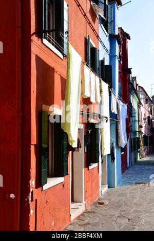 Close up view of a section of one of the old buildings in Burano close to Venice with colorful facade and laundry out to Stock Photo