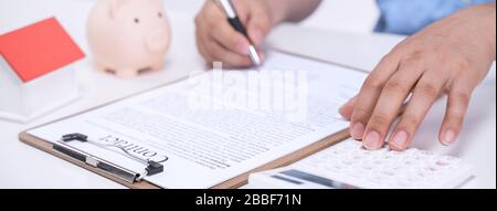 Business concept - Young Asian man in blue shirt calculates, signs agreement contract to buy a house loan payment, paying insurance, tax, close up. Stock Photo