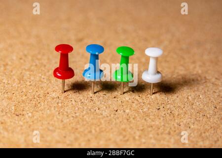 4 colourful pins stuck in the row in cork board Stock Photo