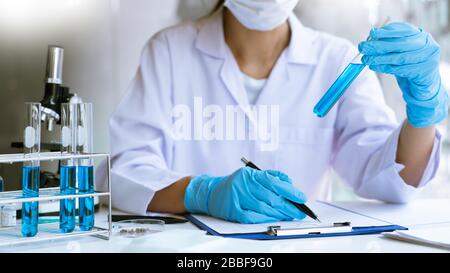 Scientist wear lab coat and protective wear are working with research or doing investigations with test tubes in experiment, Laboratory and developmen Stock Photo