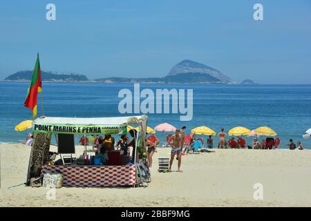 Rio de Janeiro, Brazil-February 2019; sea view of Ipanema beach with sunbathers, flags waving and a stand for soda Stock Photo