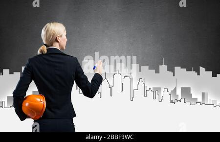 Businesswoman draws silhouette of business center Stock Photo