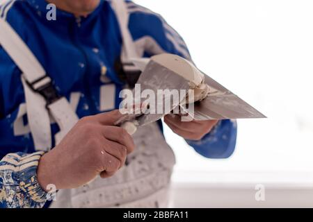 young professional construction worker plastering on gypsum walls inside the new big modern two levels apartment Stock Photo