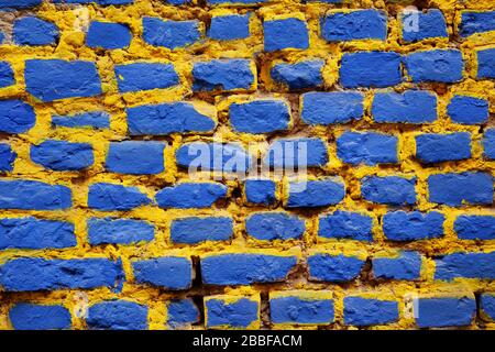 Brick wall painted in blue and yellow Stock Photo