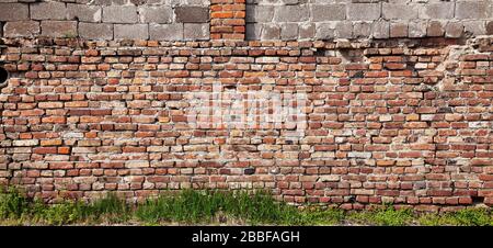 The dilapidated old brick wall made of red brick Stock Photo