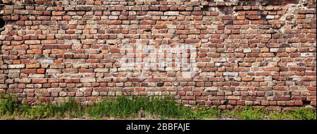 The dilapidated old brick wall made of red brick Stock Photo