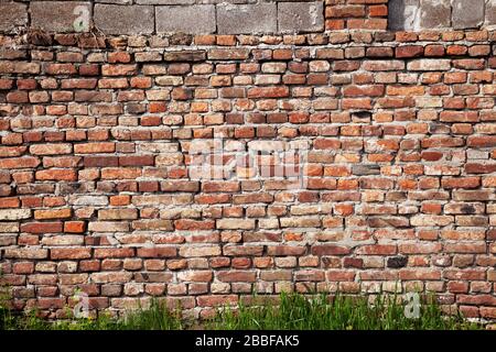 The dilapidated old brick wall made of red brick Stock Photo