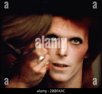 man in fancy dress, comedy costume as a ziggy stardust david bowie, space  age character, with shiny silver suit, wig & platforms Stock Photo - Alamy