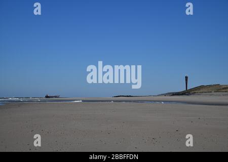 Maasvlakte Beach, Rotterdam, The Netherlands-March 2020: panoramic view of the beach with a family walking on a sunny day with ship and iconic radar t Stock Photo