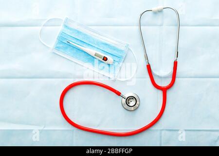 Medical mask thermometer red stethoscope, Surgical protection face mask on blue background. Doctors professional equipment. Healthcare medical concept Stock Photo