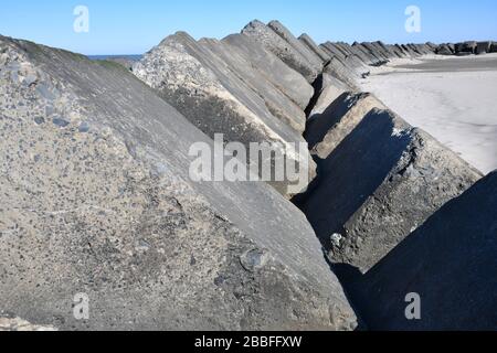 view on a long row of extreme large concrete block that act as a breakwater on the Maasvlakte beach near Rotterdam Stock Photo