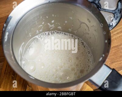 Frothy barista style oat milk in a stainless steel milk frother Stock Photo