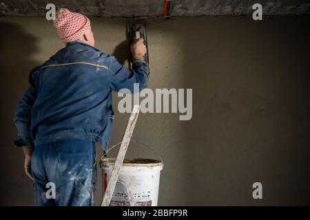 Construction worker plastering interior wall using cement plaster  Worker plastering the wall by concrete at the construction site Stock Photo