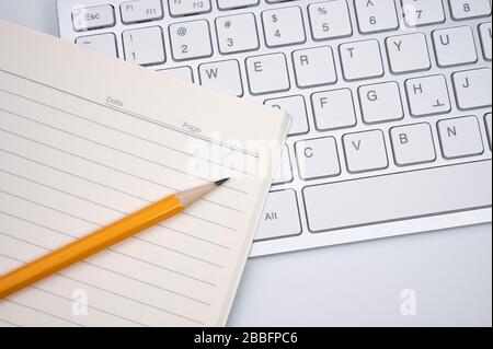 Online learning concept. There are a lined notebook and a yellow pencil on the keyboard of the laptop. Stock Photo