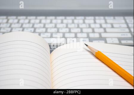 Online learning concept. There are a lined notebook and a yellow pencil on the keyboard of the laptop. Stock Photo