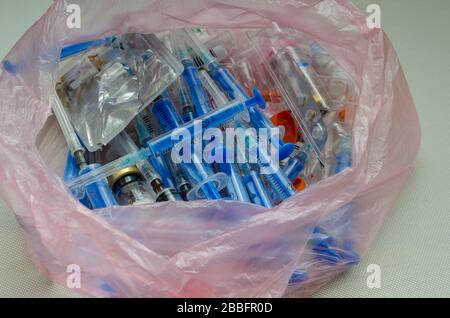 Used syringes, vials and ampoules in a bag. Cellophane bag with medical waste. Medical instruments for disposal. Close-up. Selective focus. Stock Photo