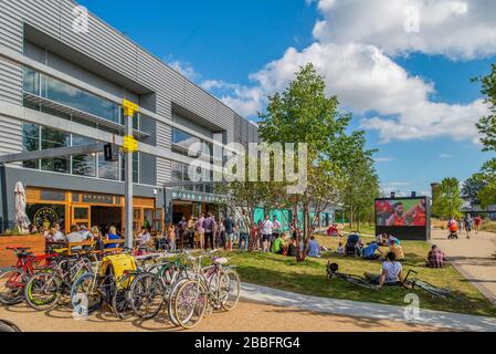 Diners and drinkers eating outside at a busy row of chain restaurants at the here east site, Queen Elizabeth Olympic Park. Stock Photo