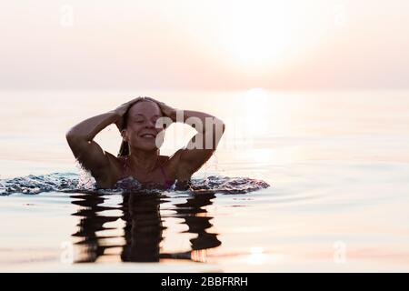 Young woman swimming in the sea in sunset