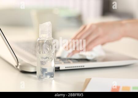 Close up of executive woman hands cleaning laptop keyboard with sanitizer on a desk in the office Stock Photo