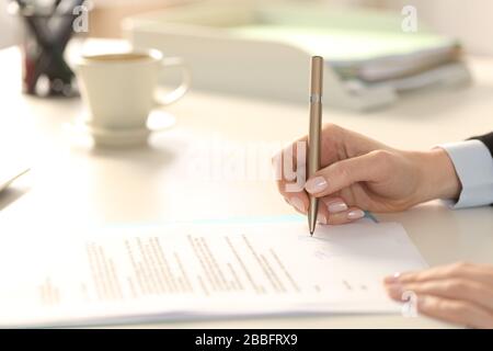 Close up of business woman hand signing contract sitting on a desk in the office Stock Photo