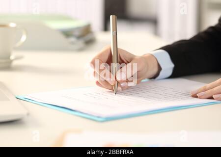 Close up of business woman hands filling out form sitting on a desk in the office Stock Photo