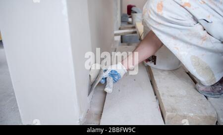 young professional construction worker plastering on gypsum walls inside the new big modern two levels apartment Stock Photo