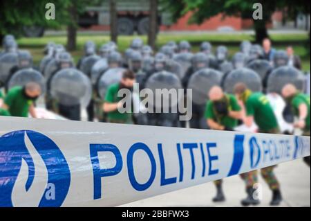 Politie / police tape in front of protesters and Belgian riot squad forming a protective barrier with riot shields Stock Photo