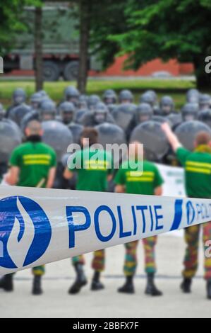 Politie / police tape in front of protesters and Belgian riot squad forming a protective barrier with riot shields Stock Photo