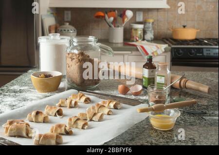 Ruglelach pastries on parchment lined baking sheet on granite island in kitchen. Stock Photo
