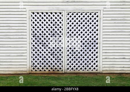 a white factory building barn with lattice wood door and grass Stock Photo