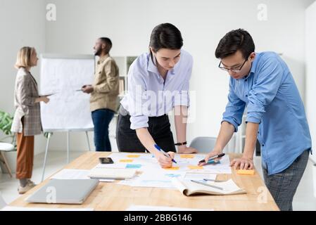 Young multi-ethnic colleagues standing at desk and planning project strategy in office Stock Photo