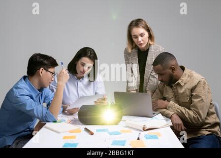 Group of thoughtful young multi-ethnic managers focused on tasks analyzing information using laptop and report data Stock Photo