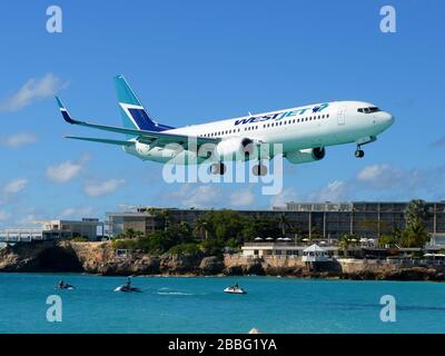 WestJet Airlines Boeing 737 passing over Maho Beach, a popular tourist attraction in St. Maarten / St Martin for the airplanes passing low. C-GRTB Stock Photo