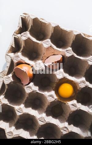 Yellow yolk and cracked eggshell in carton egg box. Easter vertical background and concept. Stock Photo