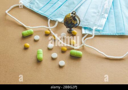 Blue medical disposable protective mask, small globe and a scattering of pills on a light background. Coronavirus concept Stock Photo