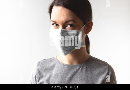 Coronavirus concept. Girl wearing a protective medical mask. Protect your health. Stop the virus and pandemic covid-19. Light gray background Stock Photo