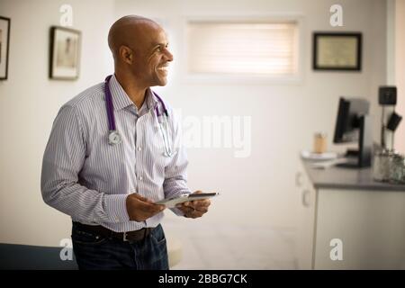 Smiling mid adult doctor holding a digital tablet. Stock Photo